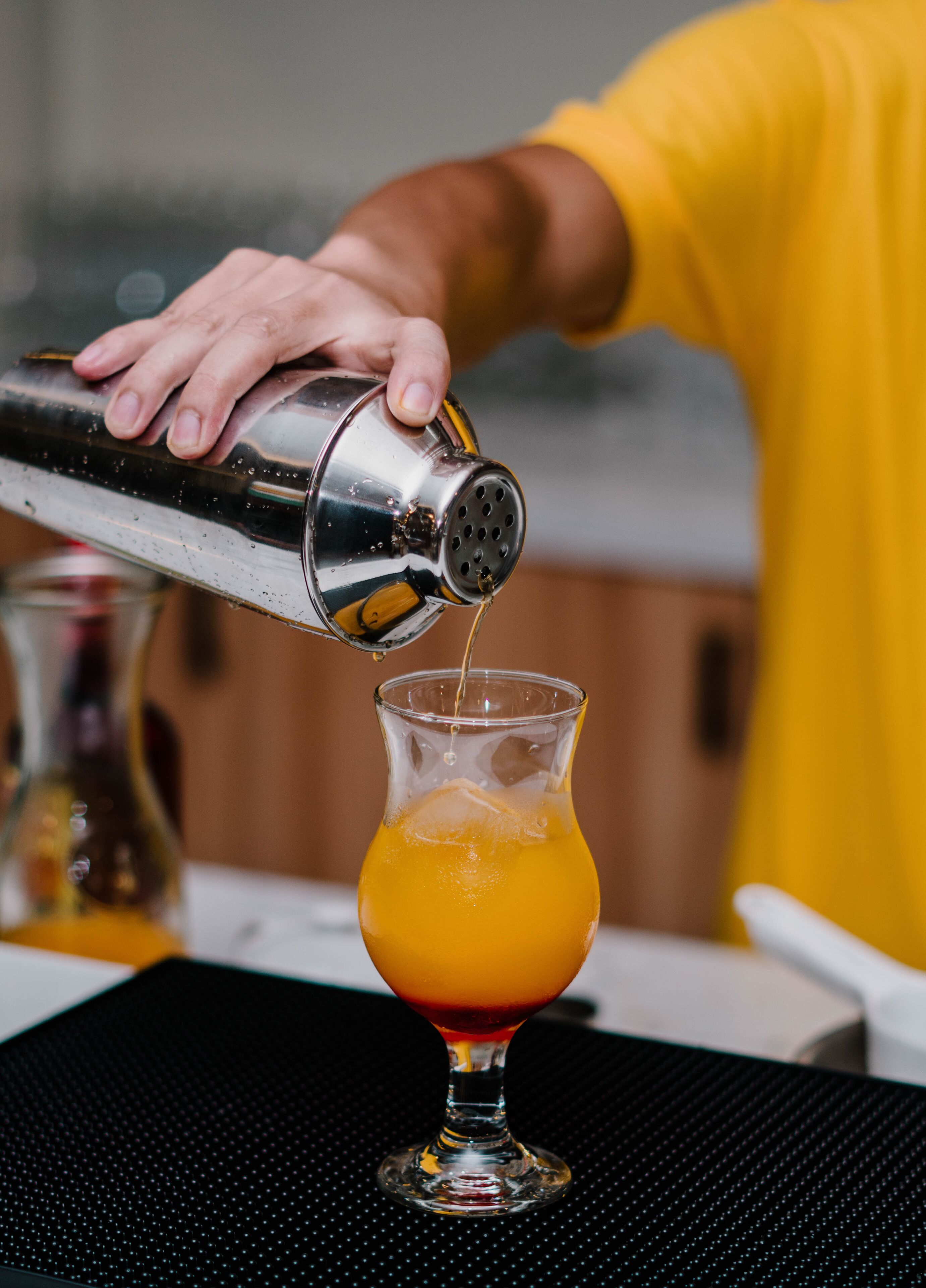 A person pouring a drink from a shaker into a glass.