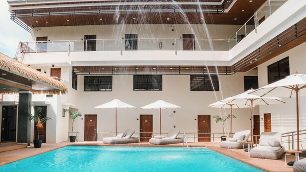 Un área de piscina cubierta con varios niveles, con vista clara a la piscina, sillones reclinables y sombrillas.