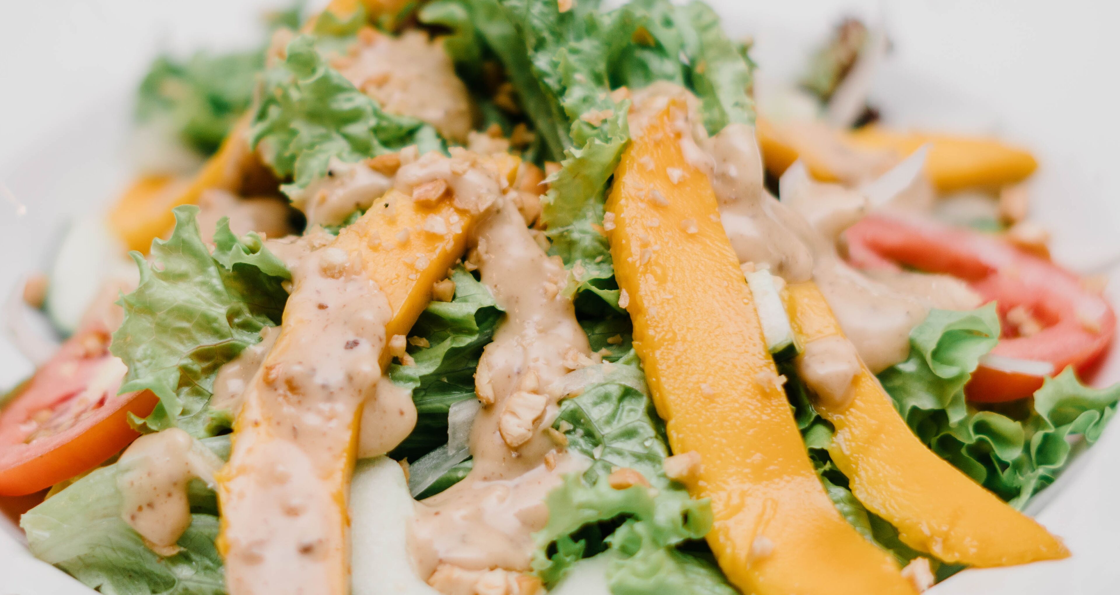 A close-up of a salad with lettuce, tomatoes, and a creamy dressing.