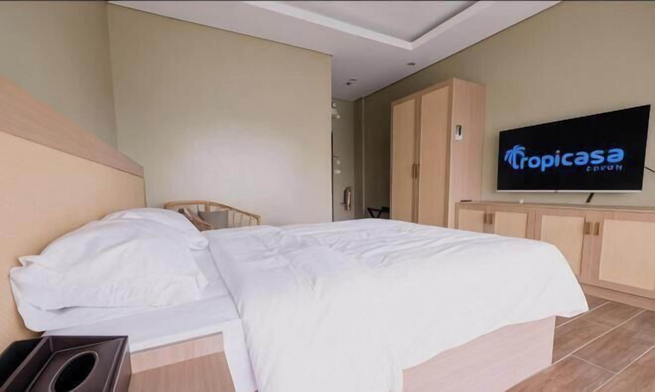 Une chambre d’hôtel avec un lit, une télévision et une armoire.