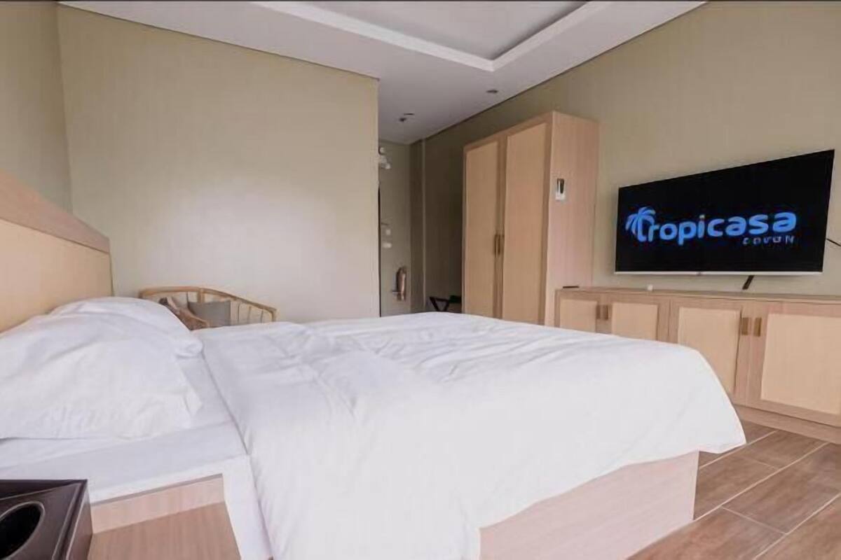 A hotel room with a bed, a television, and a cabinet.