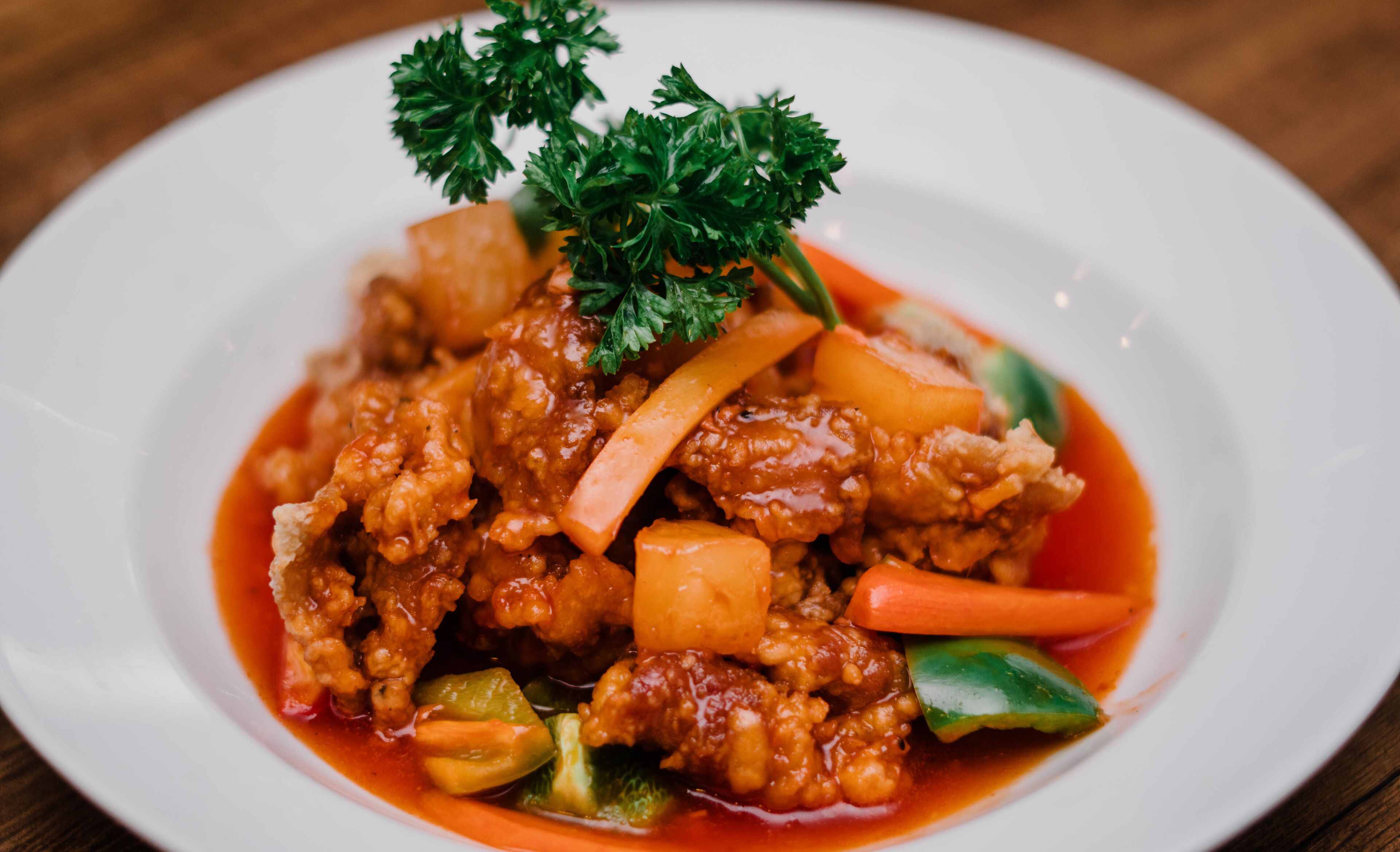 Un plato de comida con diversos vegetales y carne, decorado con perejil.