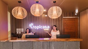 Un mostrador de recepción con dos portátiles, un panel de pared de madera y un letrero que dice "Tropicasa CORON".