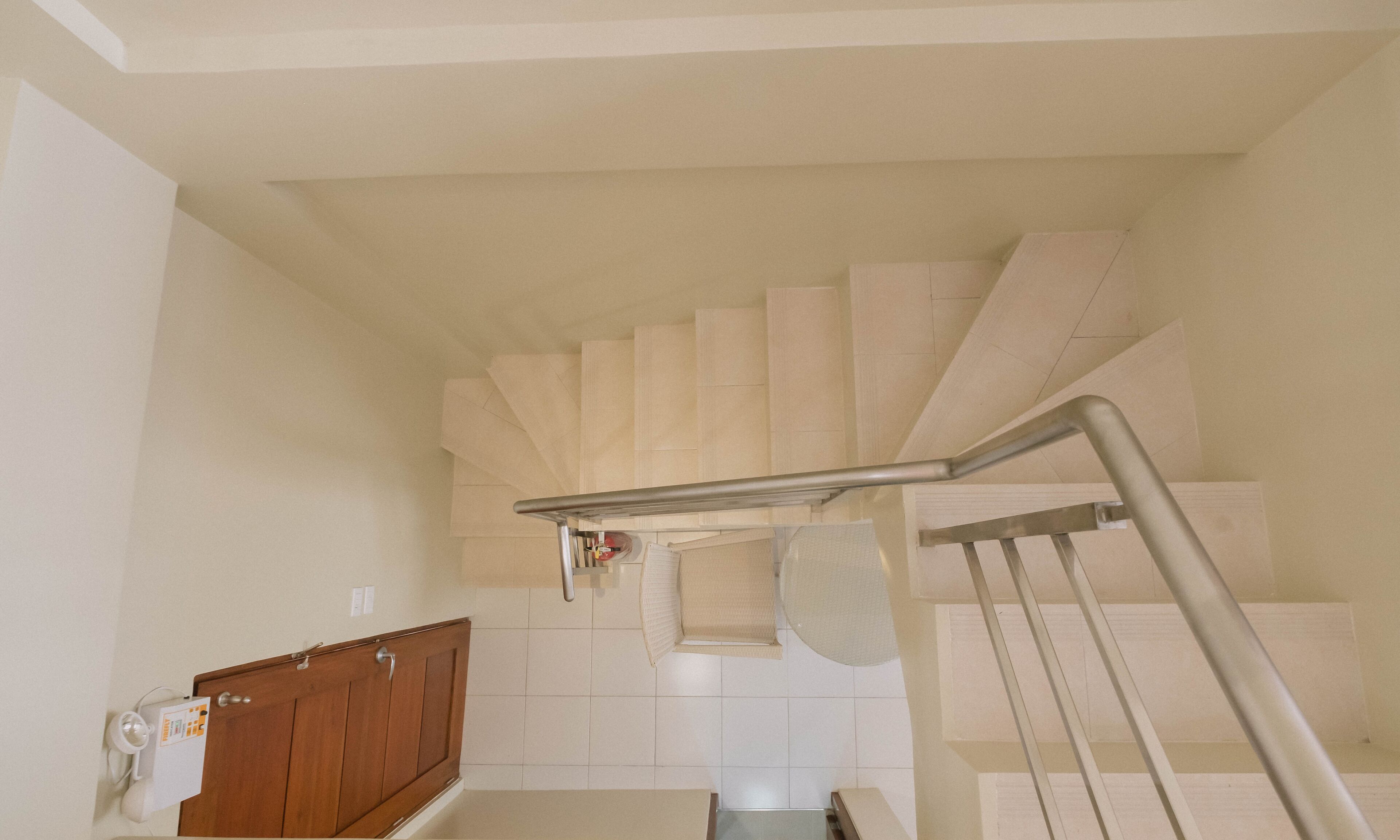A staircase with a metal handrail, wooden door, and a white wall with a tiled floor.