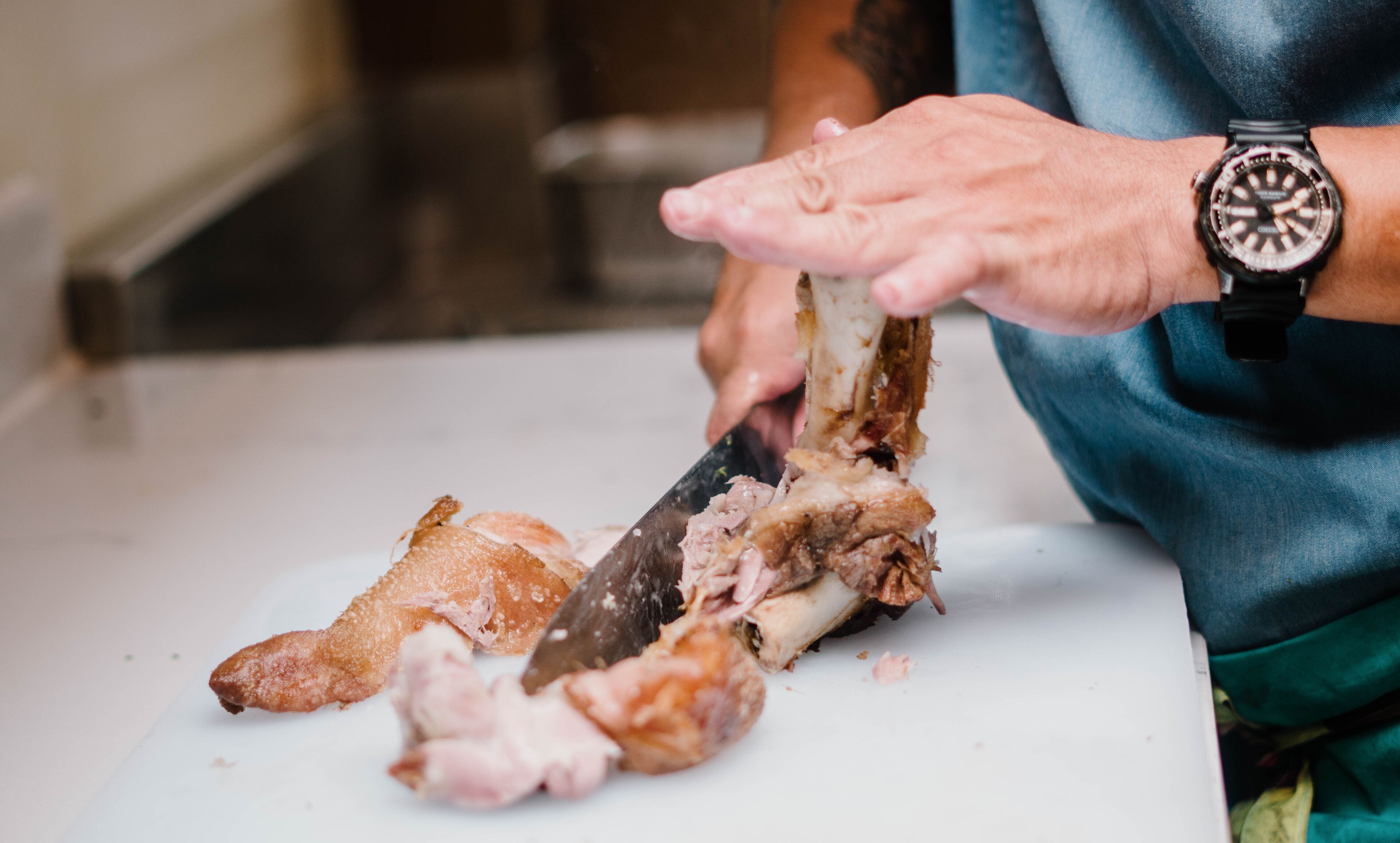 A person cutting meat on a white cutting board.