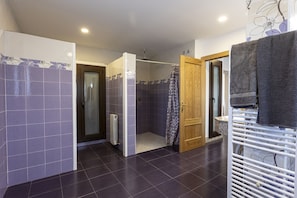 A bathroom with dark tiles, a shower area, and a wooden door. - Casa Rural Abuelo Mauri 4 Estrellas  (Mascaraque)