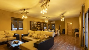 A spacious living room with a large sectional sofa, a coffee table with decorative items, and a dining area with chairs and a table.