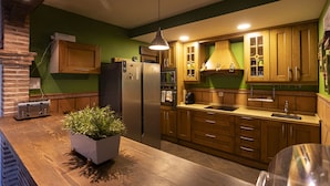 A modern kitchen with wooden cabinets, a stainless steel refrigerator, a built-in oven, and a wooden countertop.