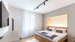 Une chambre à coucher moderne avec un lit en bois, un bureau et un téléviseur.