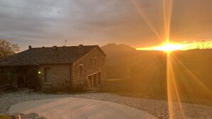 A stone building with a sloped roof, a cobblestone path, and a mountain in the background. - TERRALUNA - Holiday home surrounded by the greenery of San Leo, San Marino and Montefeltro (San Leo)