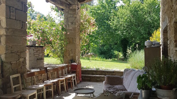 A rustic outdoor seating area with stone walls and a wooden ceiling, featuring a table, chairs, and a cushioned bench. - TERRALUNA - Holiday home surrounded by the greenery of San Leo, San Marino and Montefeltro (San Leo)