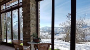 A room with large windows, wicker chairs, a small table, and a potted plant. - TERRALUNA - Holiday home surrounded by the greenery of San Leo, San Marino and Montefeltro (San Leo)