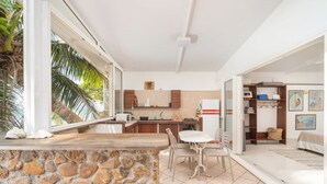 Eine moderne Küche mit einer Steinarbeitsplatte, ein Essbereich mit Tisch und Stühlen sowie ein Wohnbereich mit Sofa und Bücherregal.