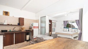 Ein kleines Hotelzimmer mit Küchenzeile, Essbereich und einem Bett.