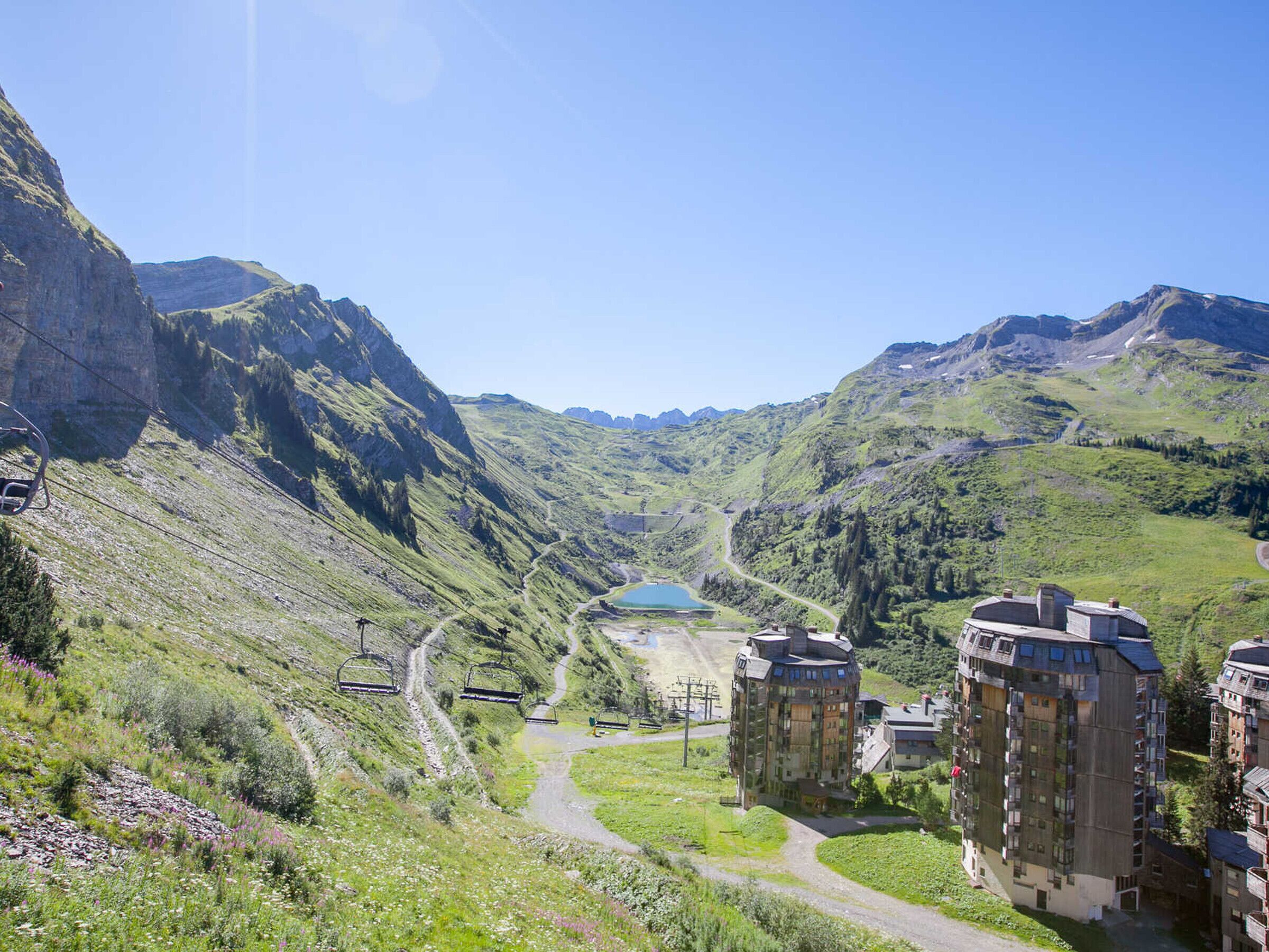 A mountainous landscape with a ski lift, a lake, and residential buildings.