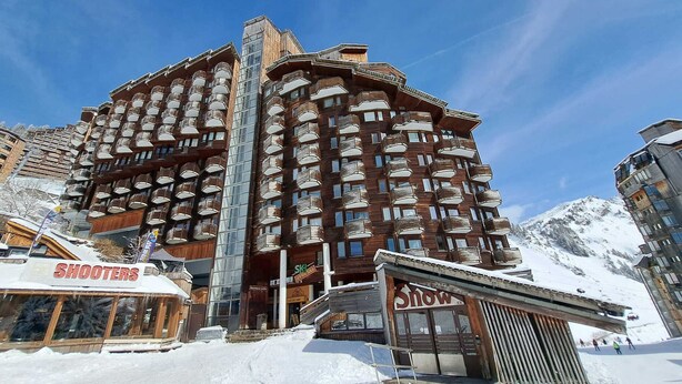 Ein mehrstöckiges Hotel mit Balkonen, einer Skipause und einem Schneefeld.