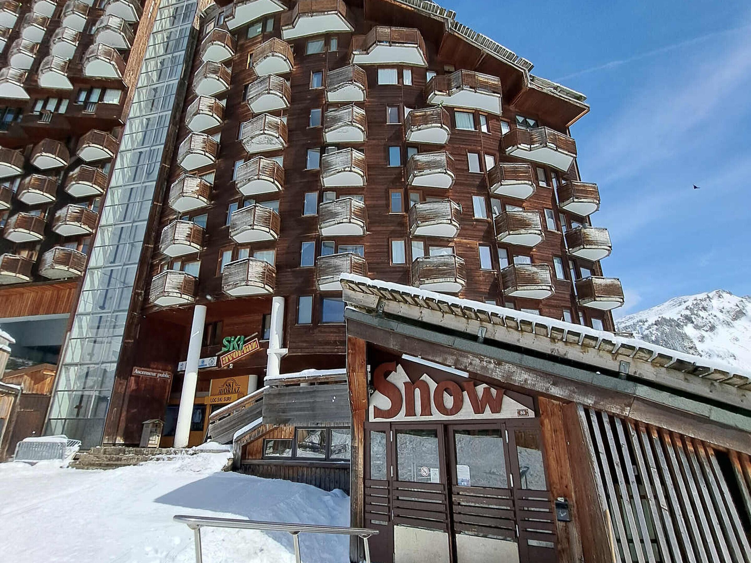 A multi-story hotel with balconies and a ski resort sign.