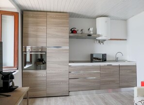 Cozinha moderna com armários de madeira, micro-ondas embutido e cafeteira.
