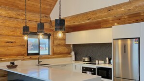 A modern kitchen with a large island, stainless steel appliances, and wooden accents. - Log cabin - beautiful, relaxing getaway with breathtaking views! (Lake Ōhau)