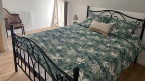 Un dormitorio con cama, una silla, una lámpara y una ventana con cortinas.