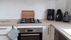 A modern kitchen with a built-in oven, a dishwasher, a gas stove, and a coffee maker.