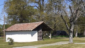 A small, single-story building with a tiled roof, surrounded by grass and trees.