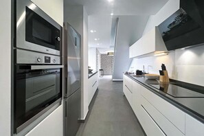A modern kitchen with built-in appliances, a central island, and a patterned wall in the background. - Salobre La Isla 7 (Maspalomas)