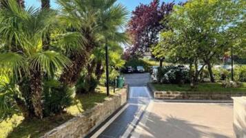 Un chemin pavé, bordé de palmiers et d’autres plantes, mène à l’entrée d’un bâtiment.