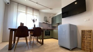 A modern kitchen with a dining area, a flat-screen TV mounted on the wall, and a sign with kitchen rules. - Cozy apartment clean and very bright equipped with all the comforts (Pescara)