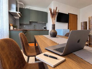 Une cuisine moderne avec un coin repas, un ordinateur portable et un carnet sur la table.