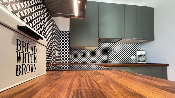A modern kitchen with a wooden countertop, patterned backsplash, and a water dispenser. - Cozy apartment clean and very bright equipped with all the comforts (Pescara)