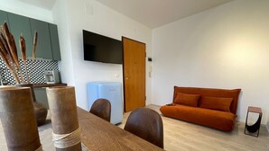A modern living room with a wooden dining table, a sofa, and a television mounted on the wall. - Cozy apartment clean and very bright equipped with all the comforts (Pescara)