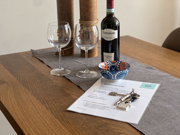 A wooden table with a bottle of wine, two glasses, a decorative bowl, and a menu.