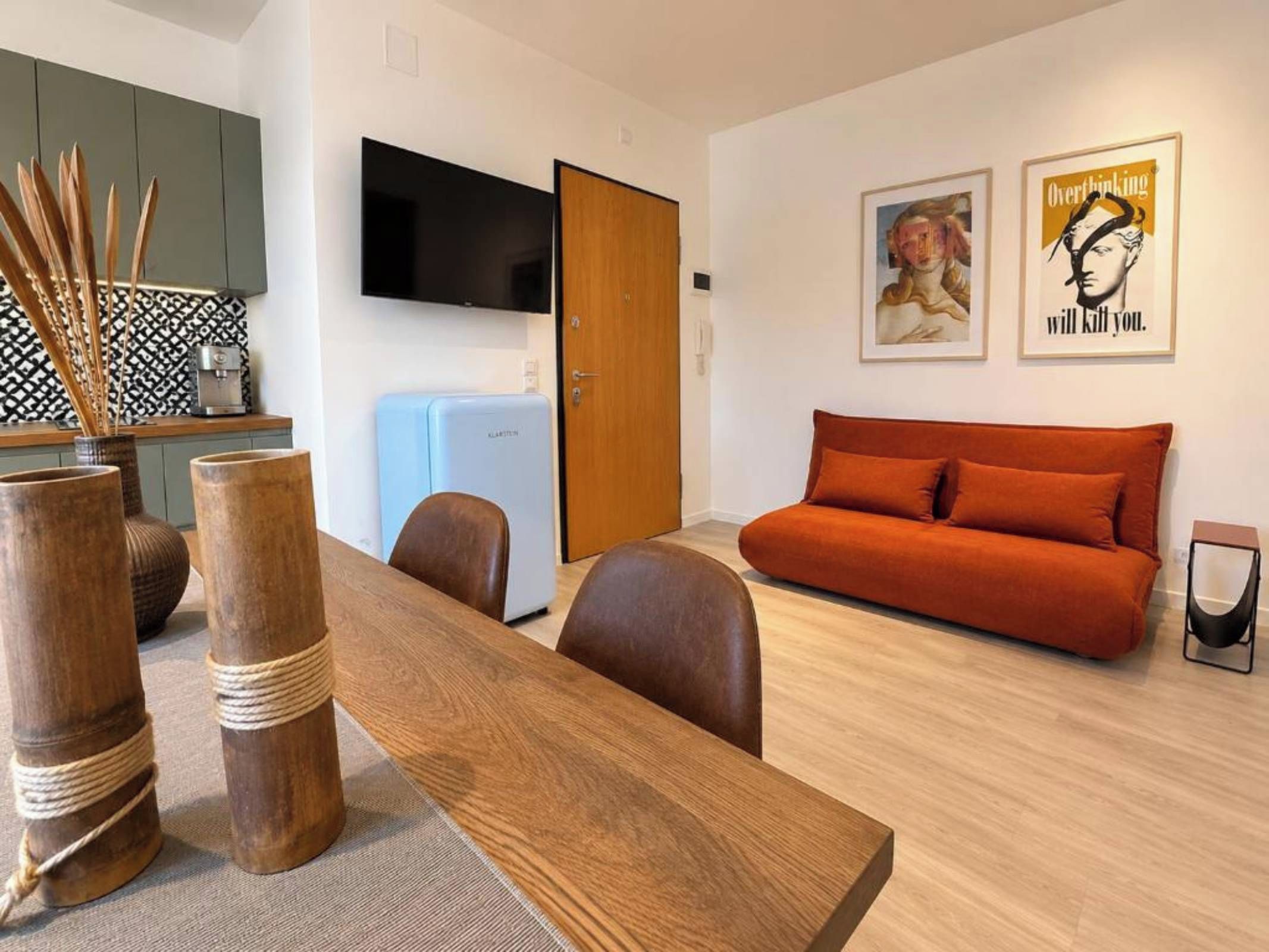 Una sala de estar moderna con un sofá, una mesa de comedor y una cocina con cafetera.