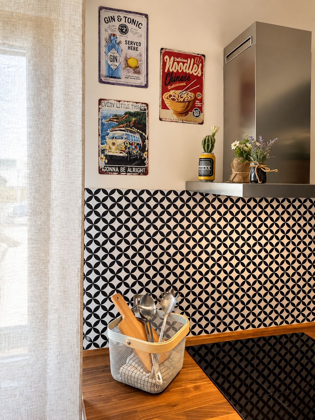 Una cucina con piastrelle a tema retrò, un frigorifero in acciaio inossidabile e manifesti d'epoca.