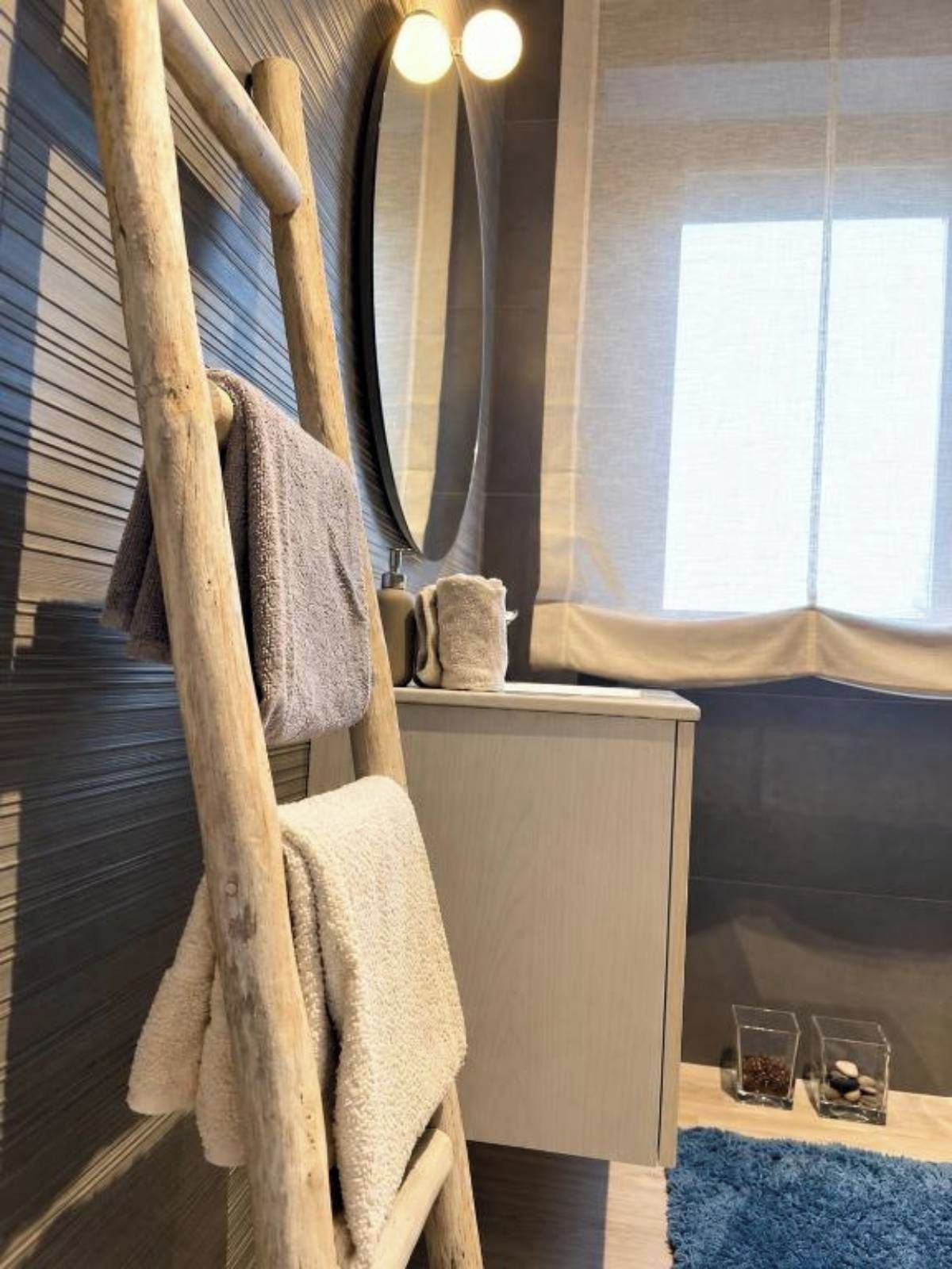 Ein Badezimmer mit einer Holzleiter, einem Spiegel, einem Waschbecken und einem Fenster.