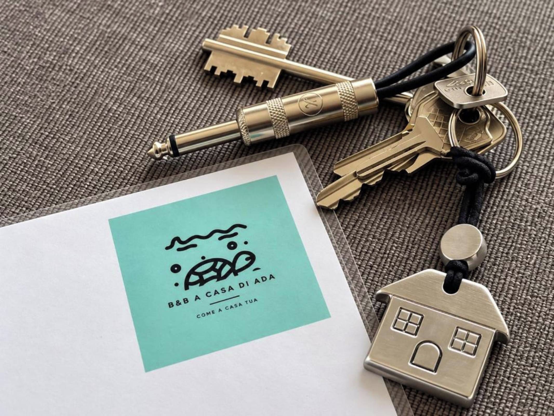 A set of keys, a house-shaped keychain, and a business card with a logo and text.