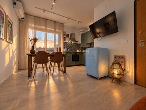 Une cuisine moderne avec un réfrigérateur bleu, une table à manger en bois et des chaises.