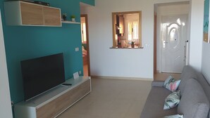 Un salon doté d’un téléviseur à écran plat, d’un canapé gris et de murs de couleur turquoise.