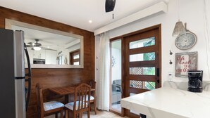 Een moderne keuken met een houten eethoek, een koelkast, een koffiezetapparaat en een klok aan de muur.