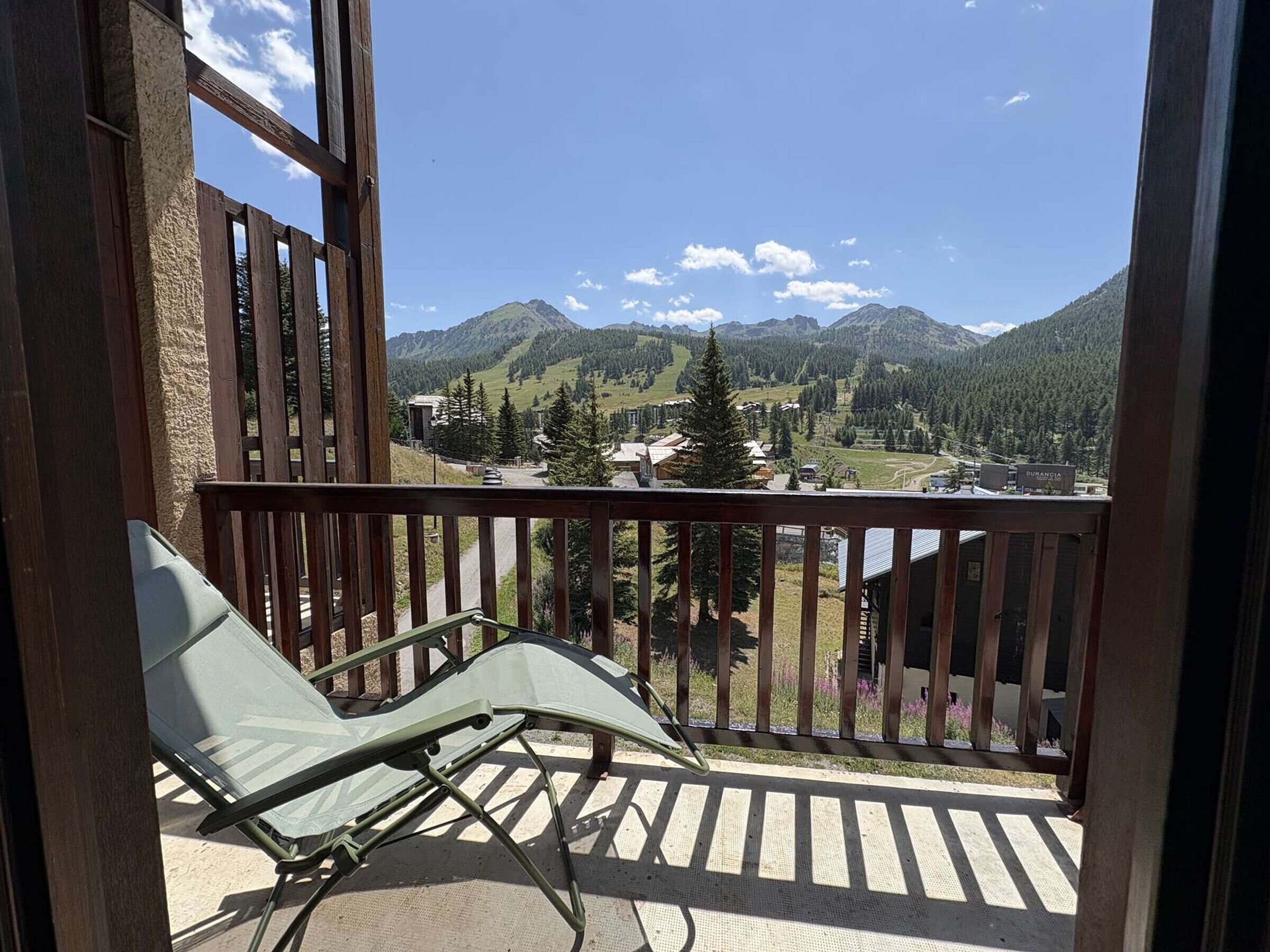 Un balcon donnant sur un paysage montagneux, avec une chaise et une balustrade en bois.