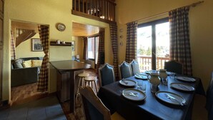 Un coin repas avec une table dressée pour quatre personnes, un canapé et un escalier menant à l’étage supérieur.