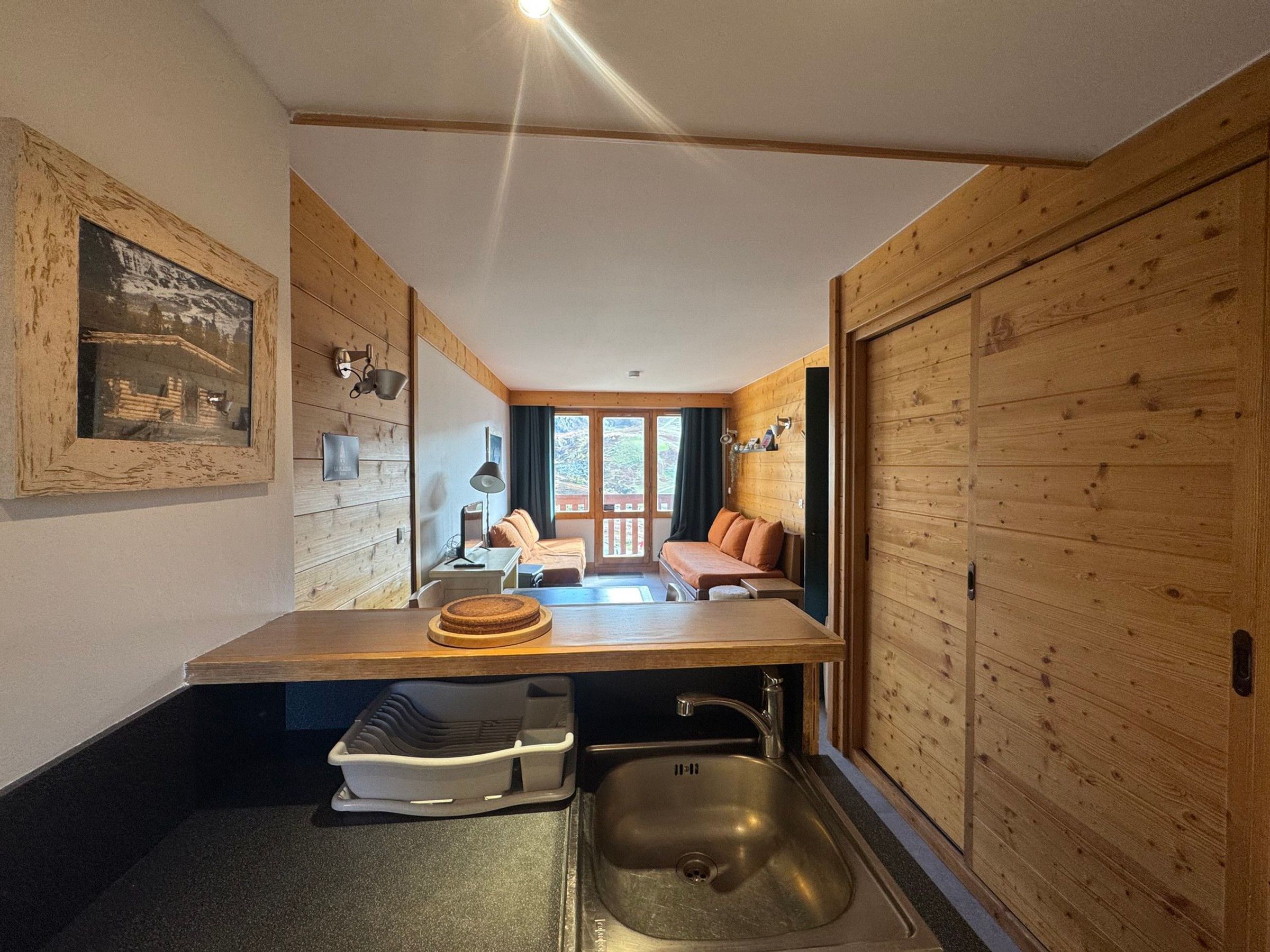 A compact room with a kitchenette, a bed, and a view of the outdoors.
