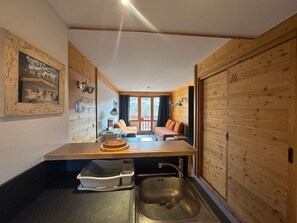 A compact room with a kitchenette, a bed, and a view of the outdoors.
