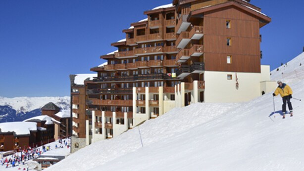 A multi-story hotel with balconies, ski slopes, and a skier. - 3-Room Apartment · Ski-In/Ski-Out · Balcony · 7 ppl (Belle Plagne)