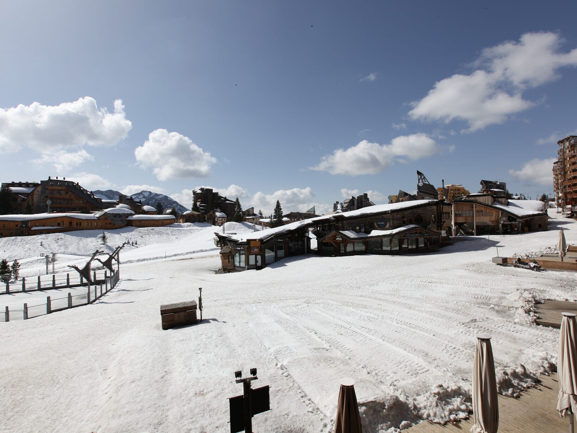 A snow-covered ski resort with rustic buildings and a clear sky.