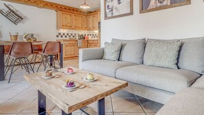 A cozy living room with a grey sofa, a wooden coffee table, and a kitchen in the background. - Premium 3-room Apartment, WiFi, 6 people in Champagny en Vanoise (Champagny-en-Vanoise)