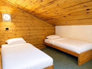 A small, cozy room with two wooden bunk beds and a single bed, featuring a simple, rustic design.