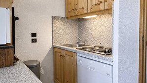 Una cocina compacta con armarios de madera, lavavajillas integrado y encimera de granito.