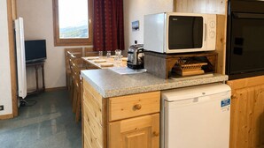 Una cocina funcional con microondas, tostadora y refrigerador pequeño.